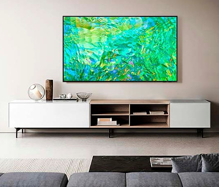Ein Samsung 4K Crystal UHD TV »GU« zeigt abstrakte grüne Kunst in einem Wohnzimmer.