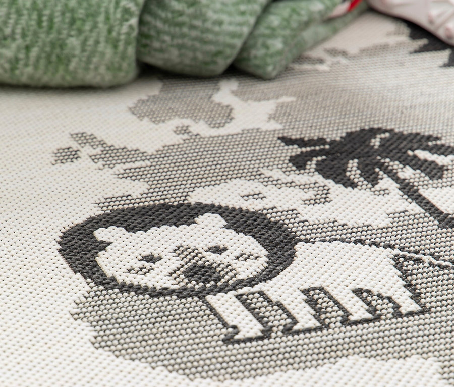 Detailaufnahme eines Kinderteppichs LINIA mit Weltkartenmotiv, der einen Löwen und Palmen zeigt.