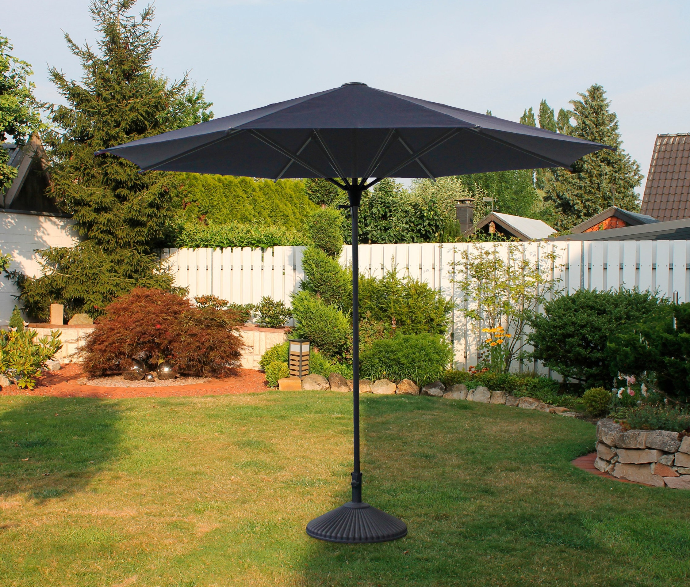 Ein blauer Leco-Sonnenschirm mit ca. 300 cm Durchmesser steht auf einer Wiese.