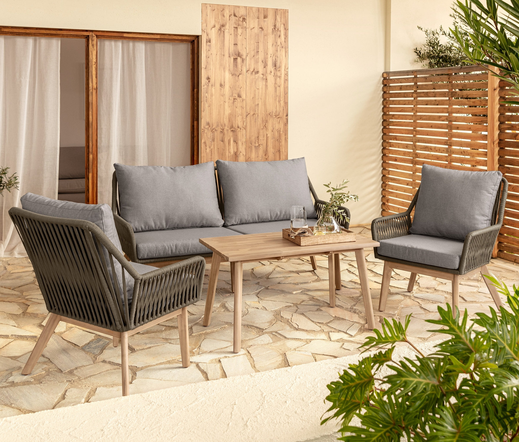 Ein Lounge-Dining-Set mit grauen Kissen auf einer Terrasse.