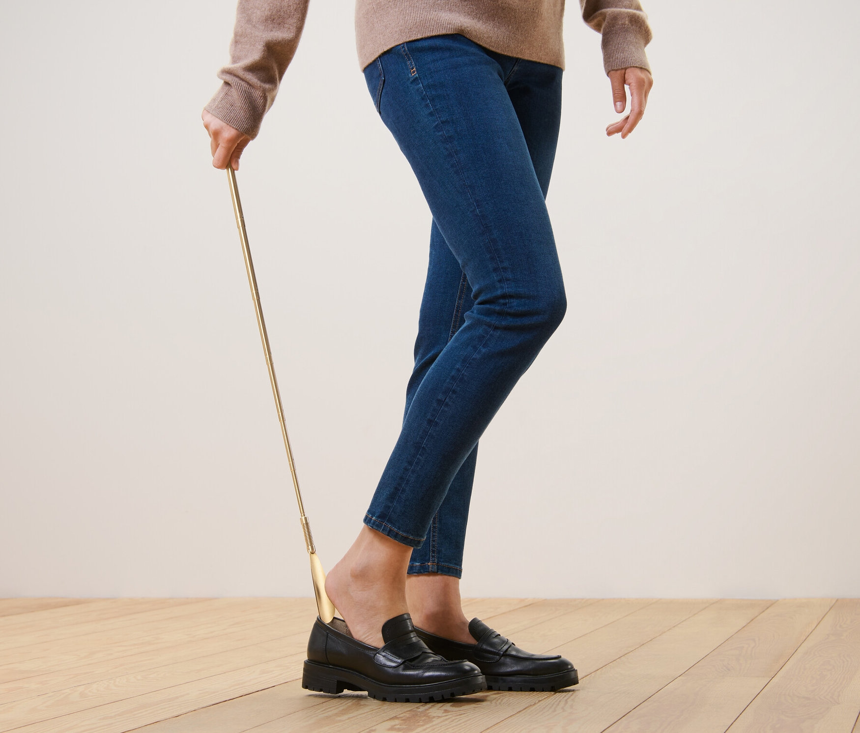 Person benutzt einen Teleskop-Schuhanzieher, um schwarze Schuhe anzuziehen.