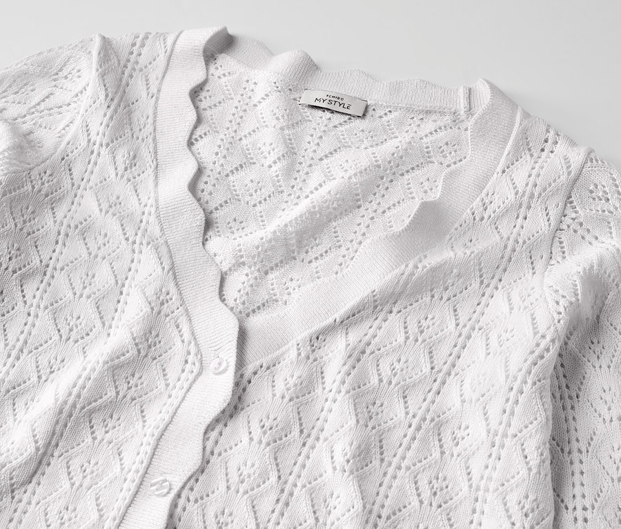Detailansicht einer weißen Strickjacke mit Ajour-Muster.