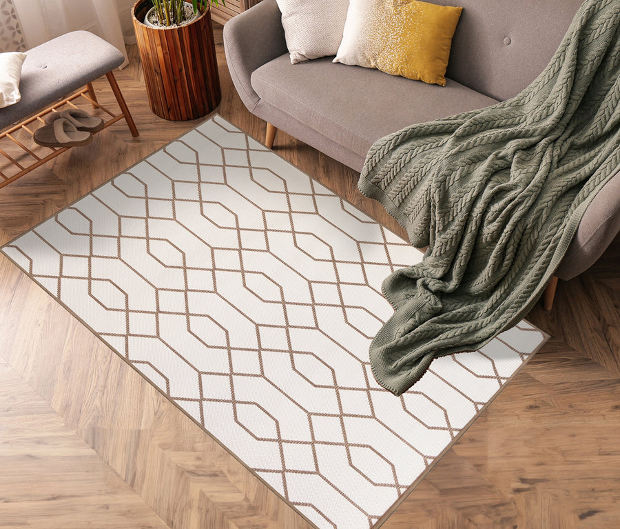 Ein brauner Outdoor-Wendeteppich »Geo River« (120 x 160 cm und 160 x 220 cm) liegt im Wohnzimmer mit grauem Sofa und grüner Strickdecke.