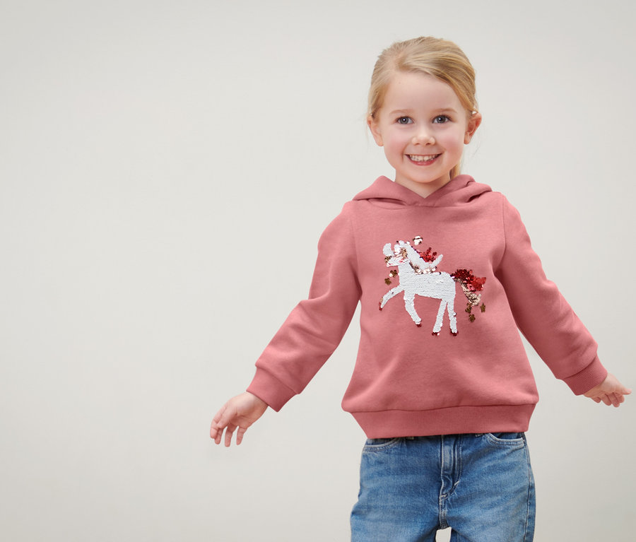 Mädchen trägt ein Kinder-Sweatshirt mit Wendepailletten, Einhorn oder Print (Gr. 86/92).