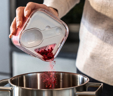 Frau schüttet rote Beeren aus einem 6-teiligen ZWILLING FRESH & SAVE CUBE Starter-Set S in einen Topf.