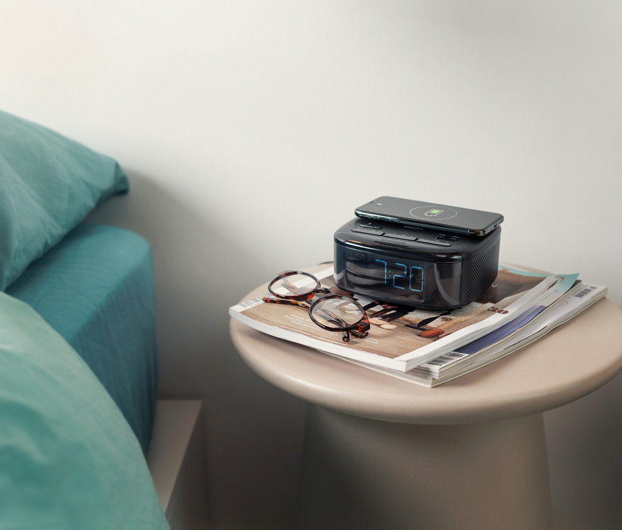 Auf einem Nachttisch stehen ein Philips DAB-Radiowecker »TAR7705« mit einem Telefon darauf und eine Brille daneben.