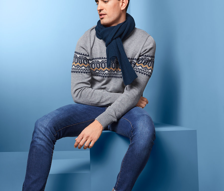 Mann sitzt und trägt einen Strickschal, dunkelblau.