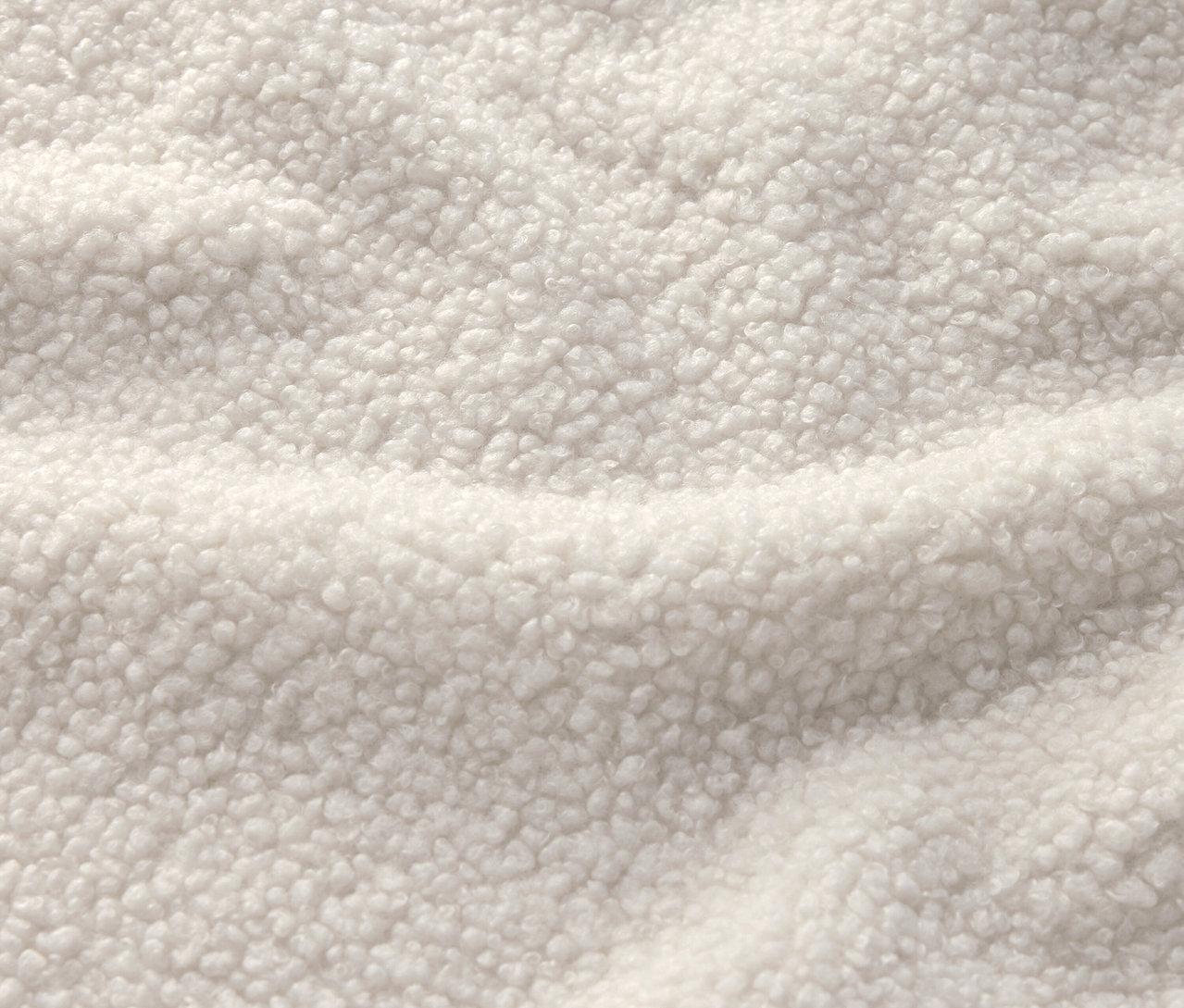 Nahaufnahme eines cremeweißen Stoffes mit Sherpa-Textur.