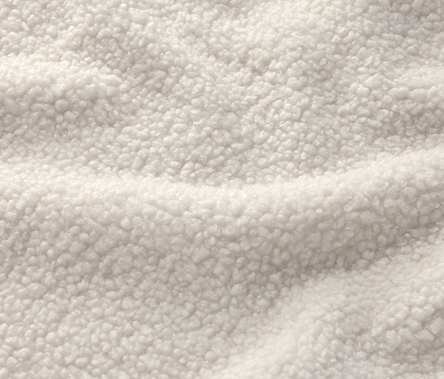 Nahaufnahme eines cremeweißen Stoffes mit Sherpa-Textur.