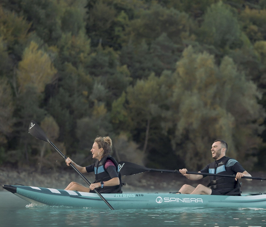 Zwei Personen paddeln in einem Spinera Hybris 410 2-Personen-Kajak auf einem See.