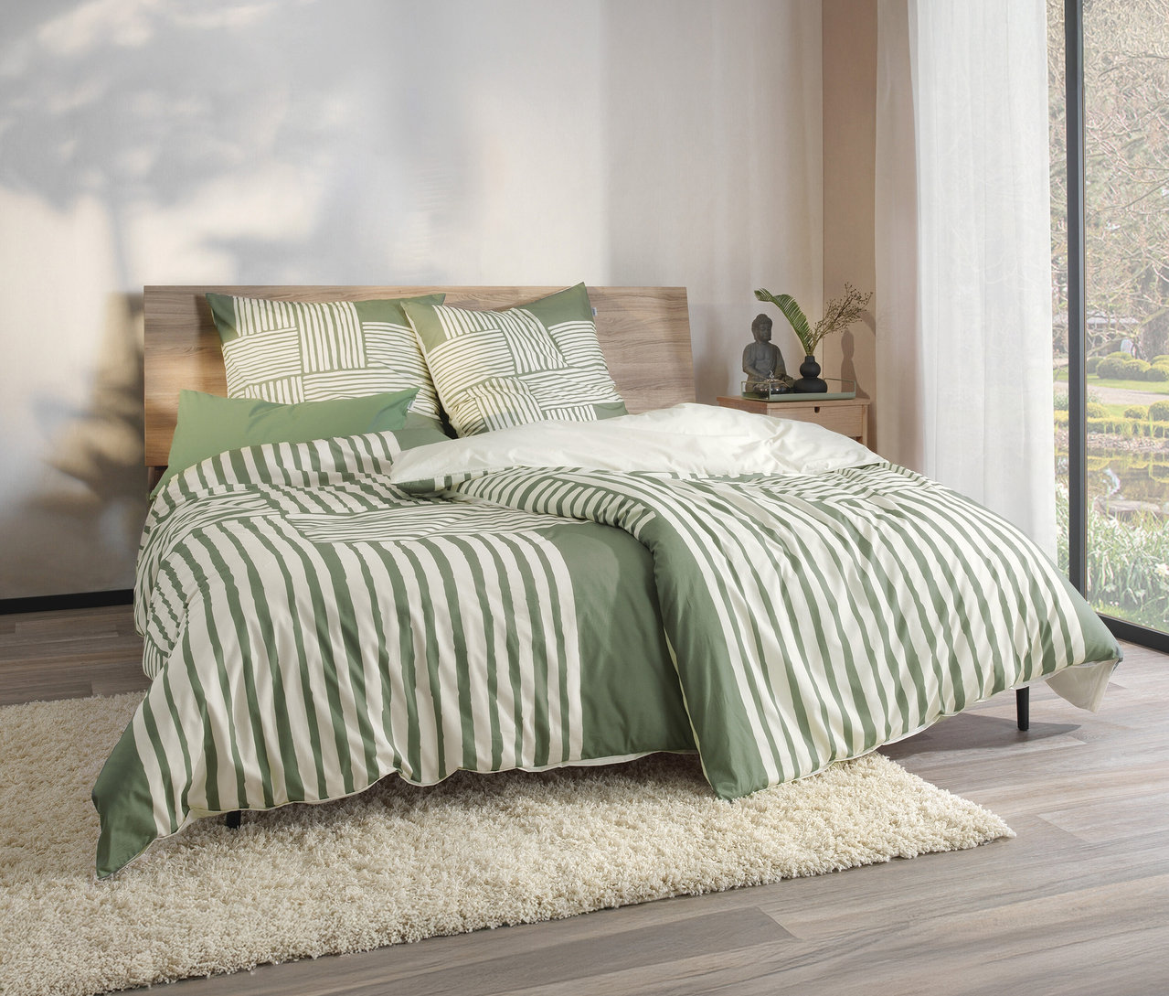 Grün gestreifte Bettwäsche auf einem Bett mit hölzernem Kopfteil. SCHÖNER WOHNEN-Kollektion Bettwäsche, grün, Übergröße.