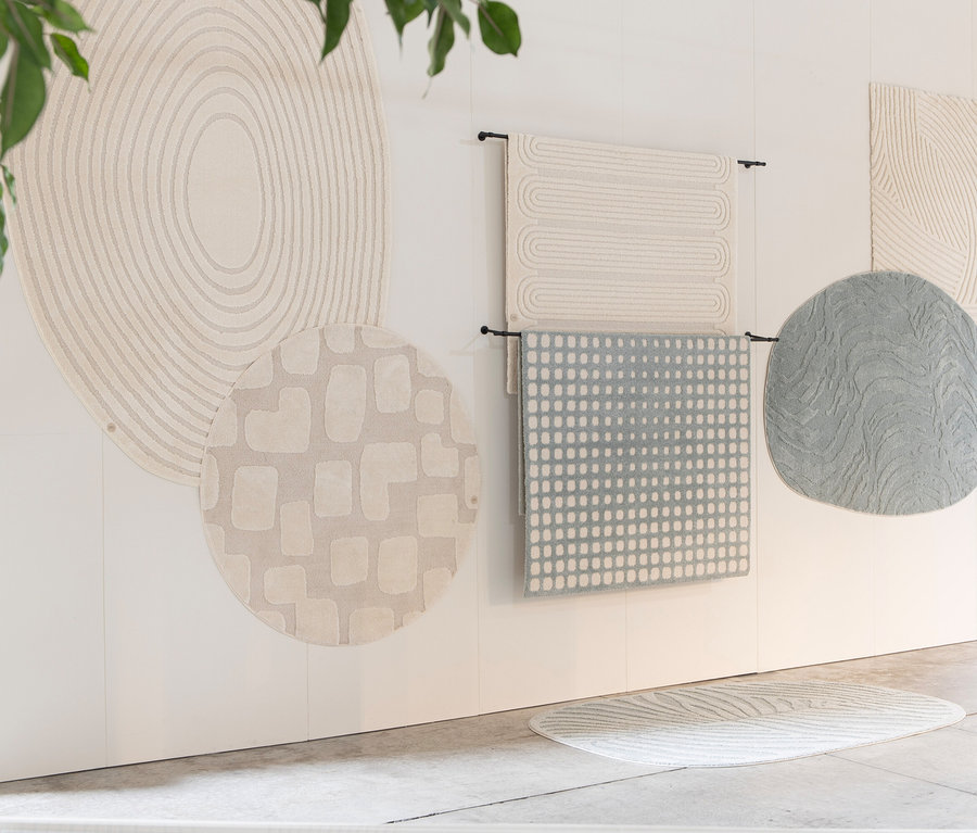Verschiedene Teppiche hängen an der Wand und liegen auf dem Boden, darunter ein Woood Teppich »Praline« 200 cm in Nougat.