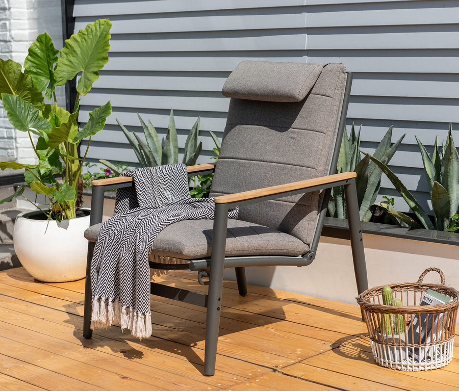 Ein anthrazitfarbener ScanCom Outdoor-Loungesessel mit verstellbarer Rückenlehne steht auf einer Holzterrasse neben einer Topfpflanze und einem Weidenkorb.