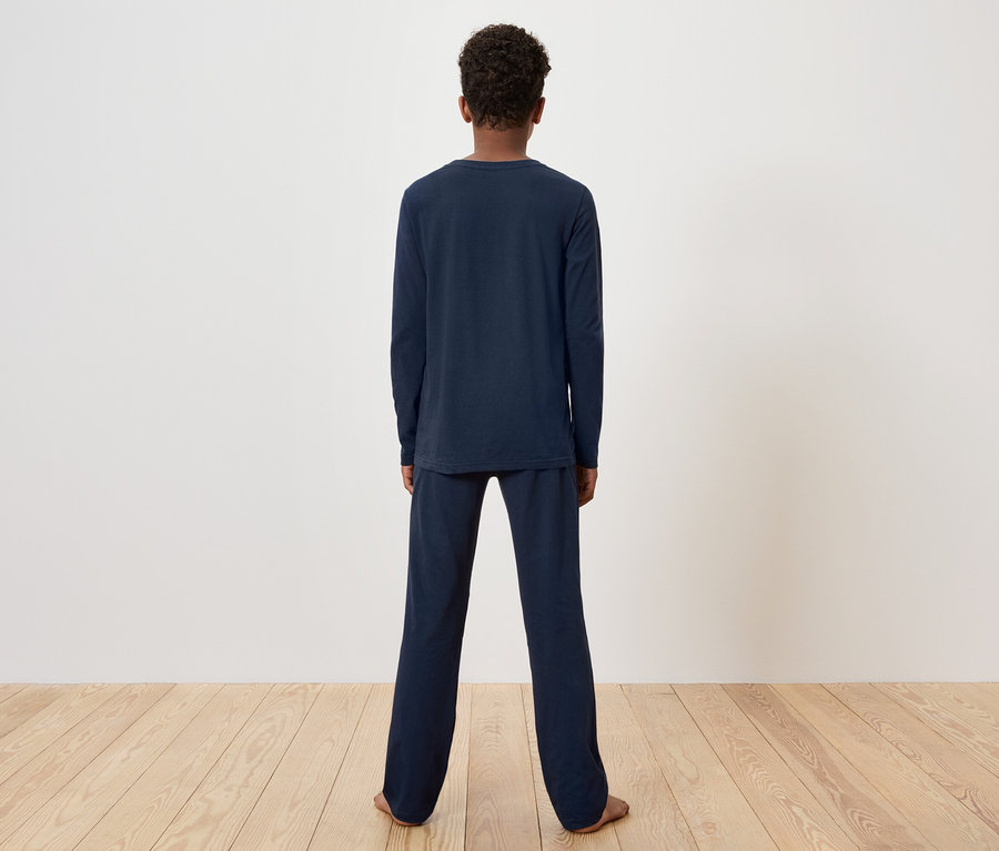 Eine Person steht mit dem Rücken zur Kamera und trägt einen dunkelblauen Pyjama.