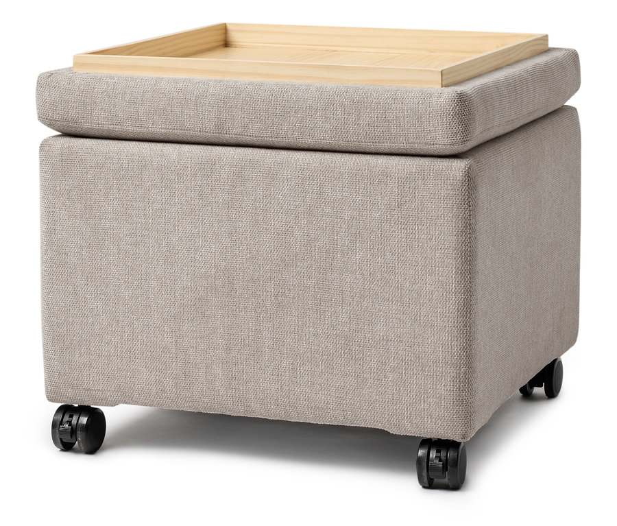 Ein beiger Stoffwürfel mit einem Holztablett oben drauf und Rädern.
