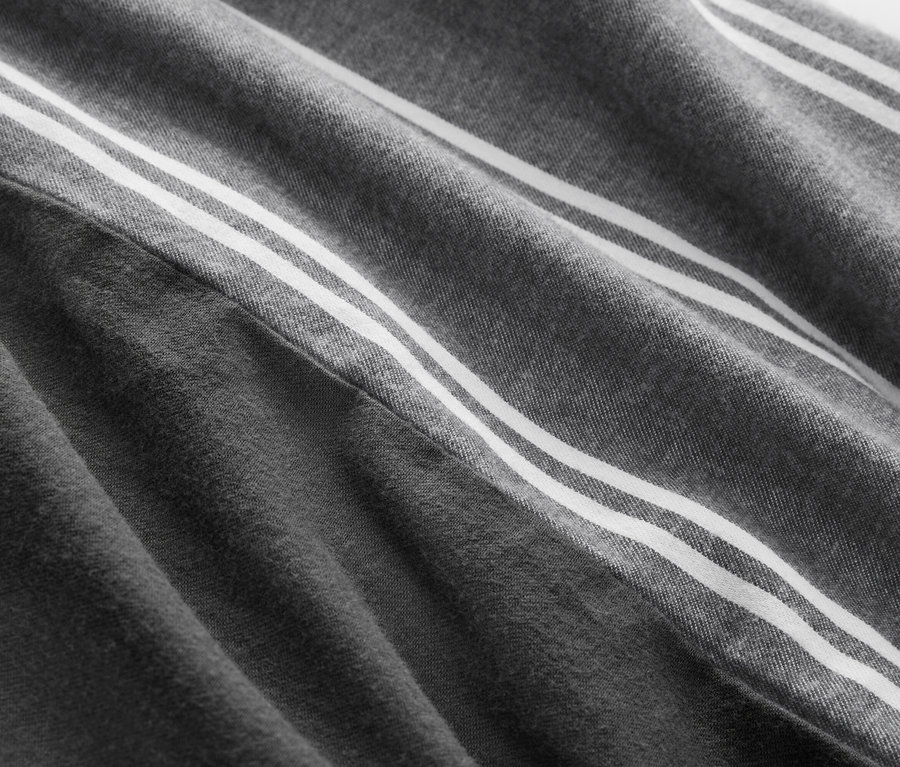 Detailaufnahme eines grauen Stoffes mit drei weißen Streifen.