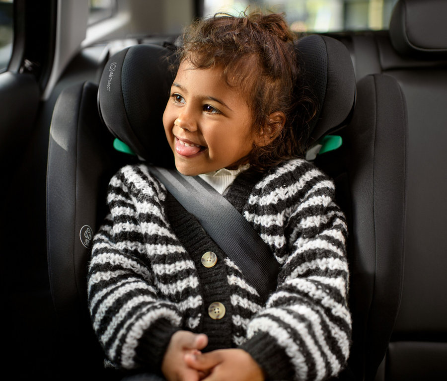 Lächelndes kleines Mädchen sitzt im Maxi-Cosi Kinder-Autositz »Rodifix S«, i-Size und streckt die Zunge heraus.
