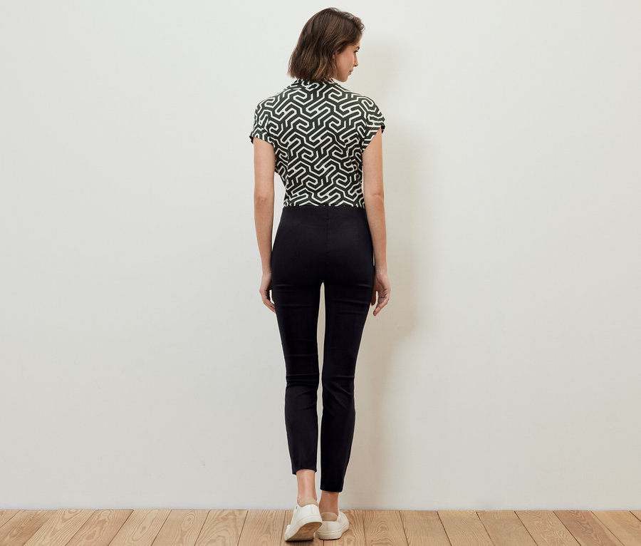 Frau steht mit dem Rücken zur Kamera und trägt eine schwarze Stretchhose.