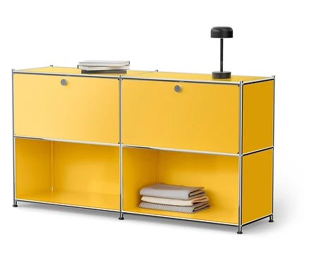 Gelber Schrank mit silbernem Rahmen, oben zwei Bücher und eine Lampe