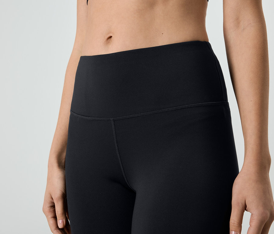 Nahaufnahme einer Frau, die eine schwarze Leggings und ein Sportoberteil trägt.