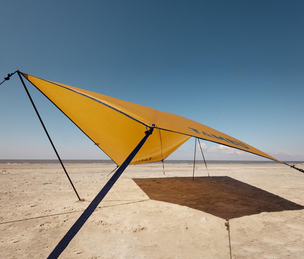 Gelbes Tambu »PALA« Tarp/Sonnensegel ist am Strand aufgestellt.