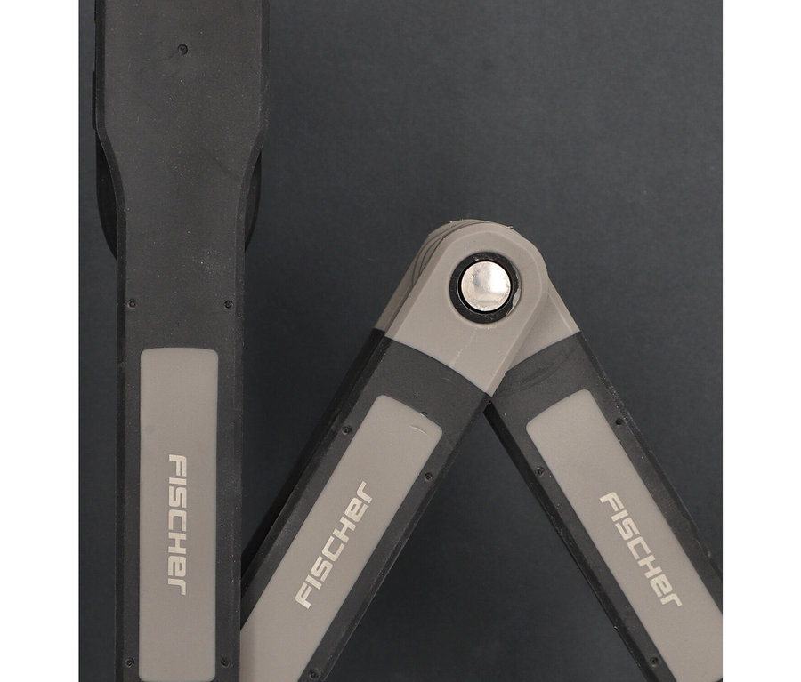 Nahaufnahme des Fischer Faltschloss Plus FK90/8 Fahrradschlosses, teilweise geöffnet auf dunklem Hintergrund.