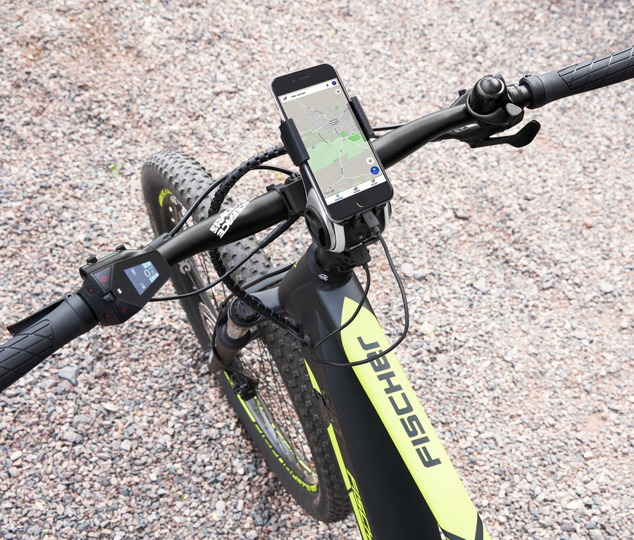 Draufsicht auf ein Fahrrad mit montierter FISCHER Fahrrad-Multimedia-Smartphone-Box, die ein Smartphone mit Navigationskarte hält.