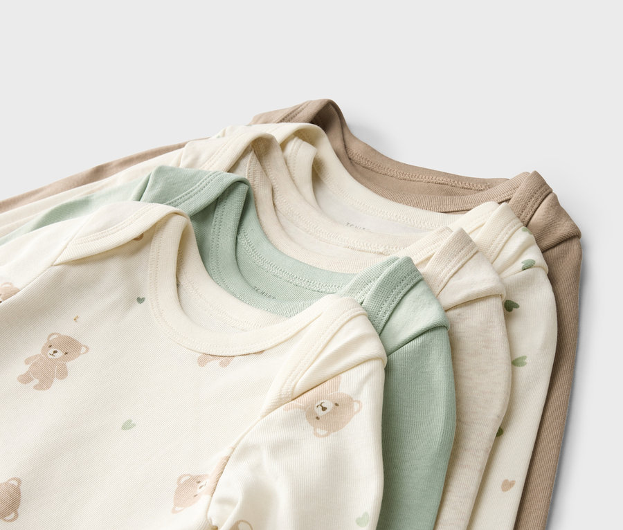 Stapel aus Babybodys in Beige, Grün und Weiß mit Bären- und Herzmotiven.