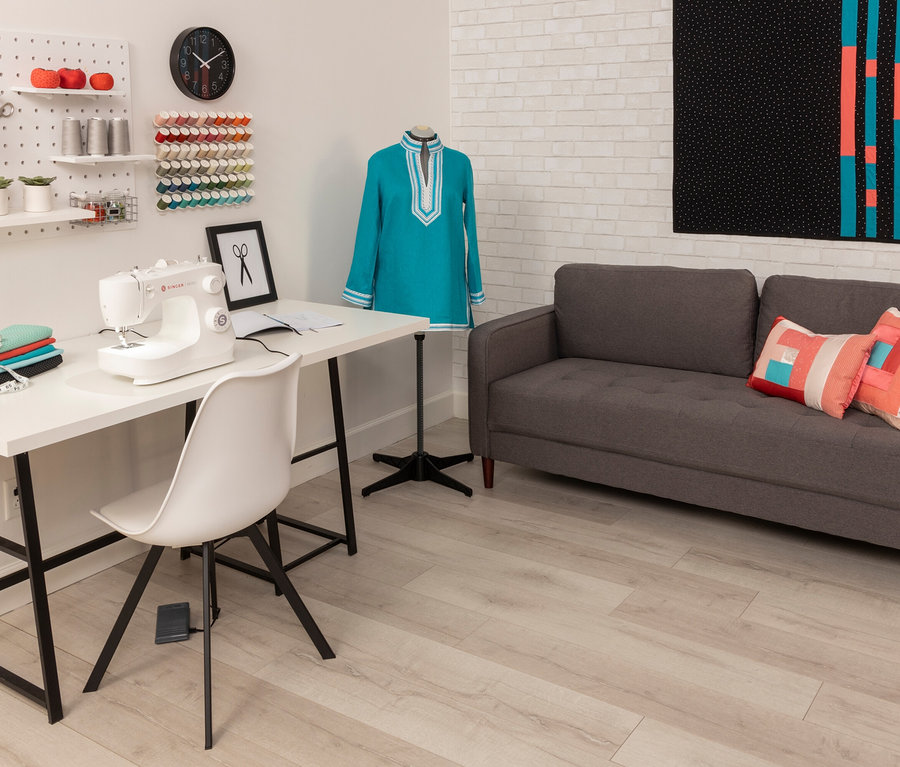 Nähzimmer mit Singer Nähmaschine »M2405« auf weißem Tisch, daneben Stoffstapel und eine Schneiderpuppe mit blauem Kleid.