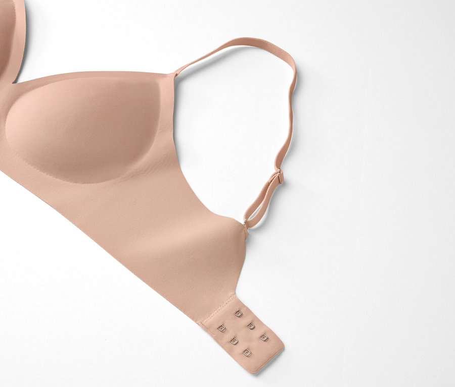 Ein hautfarbener BH liegt auf einem weißen Hintergrund.