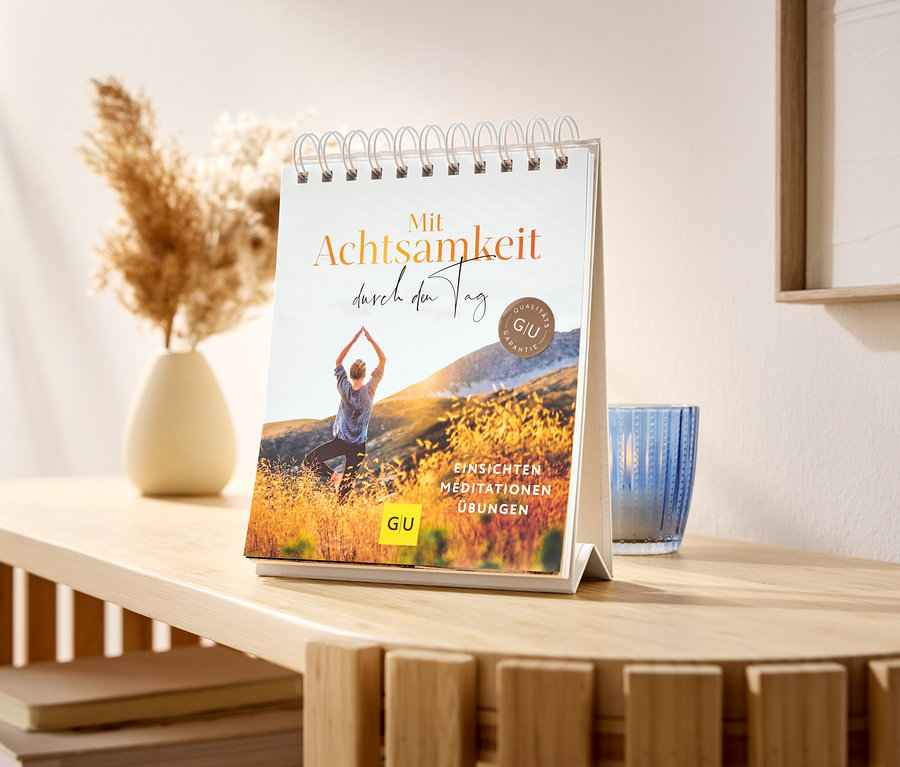 Auf einem Tisch steht ein Tisch-Aufsteller »Mit Achtsamkeit durch den Tag«.