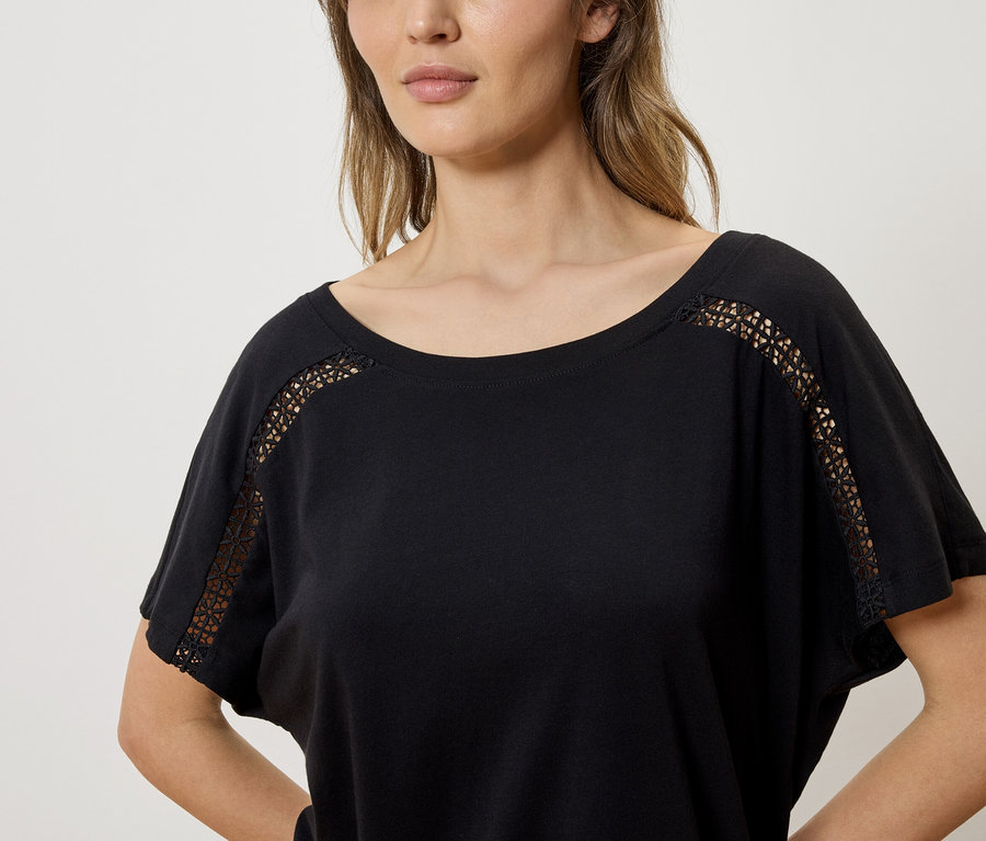 Frau trägt ein schwarzes T-Shirt mit Spitzendetails an den Ärmeln.