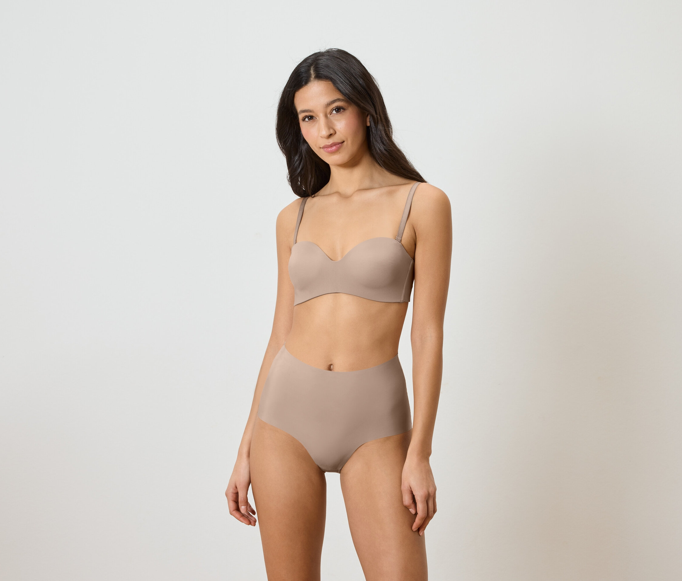 Frau trägt einen trägerlosen BH und hochtaillierte Slips in Beige.