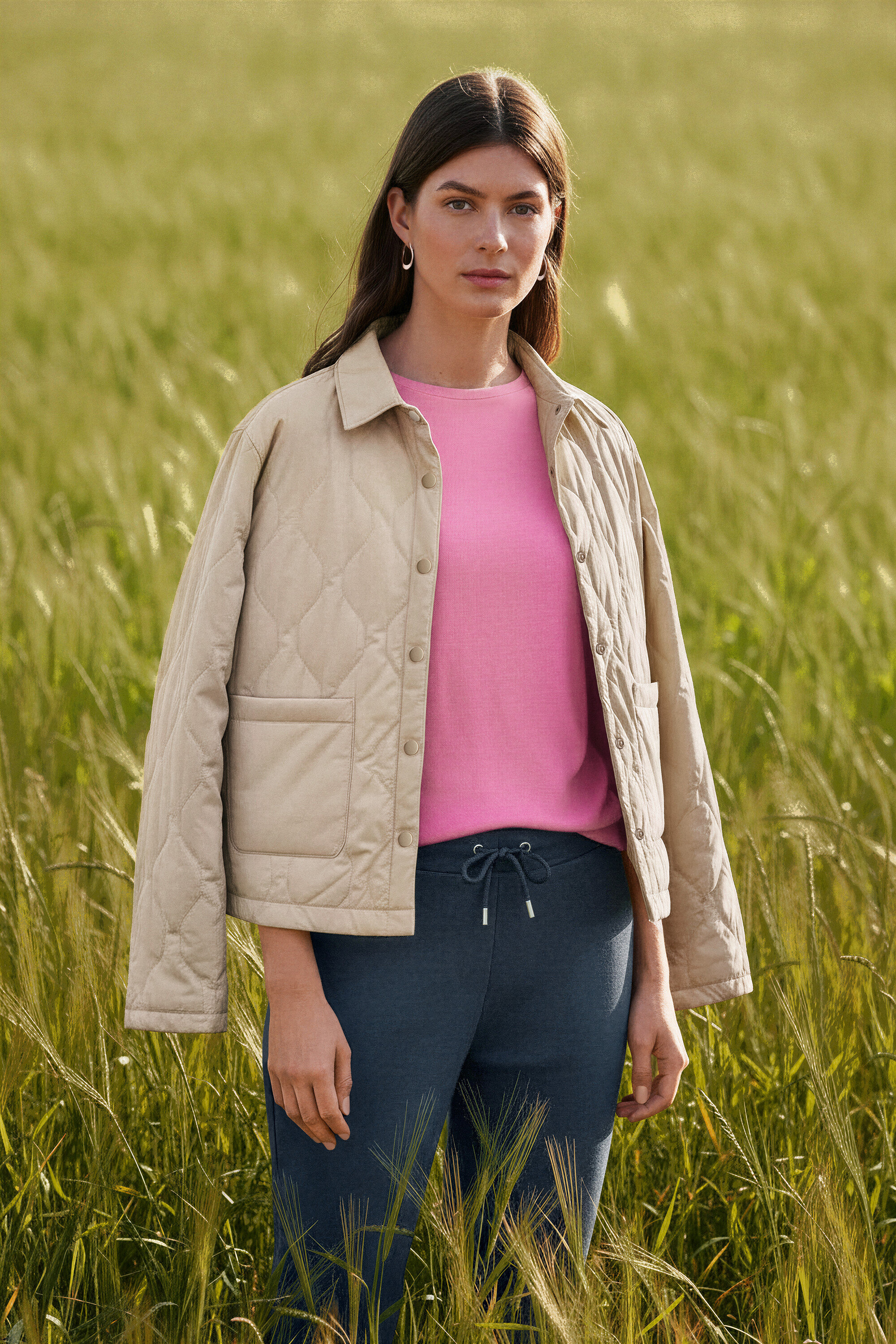 Frau steht in einem Feld und trägt Creolen Wave.