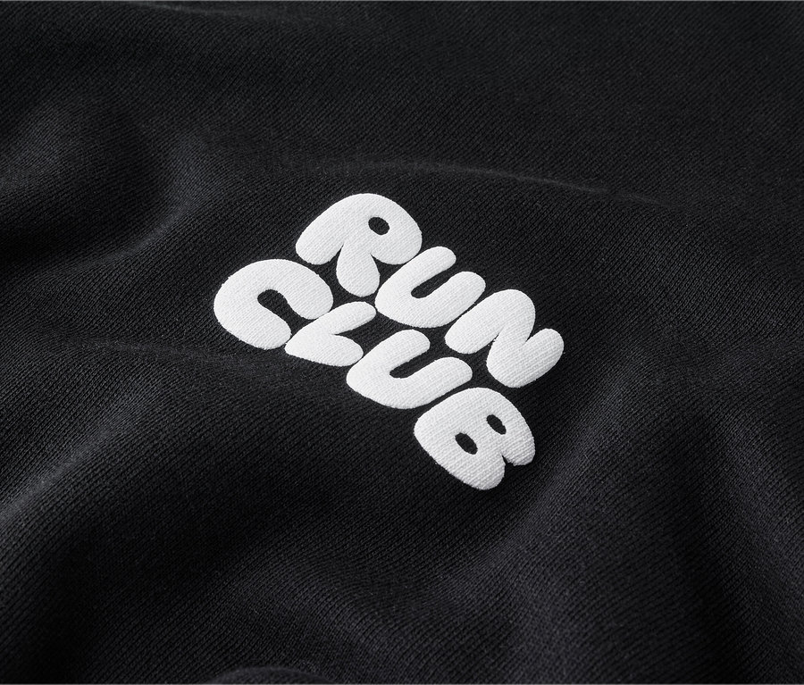 Nahaufnahme eines schwarzen Sweatshirts mit weißer Stickerei „RUN CLUB“.