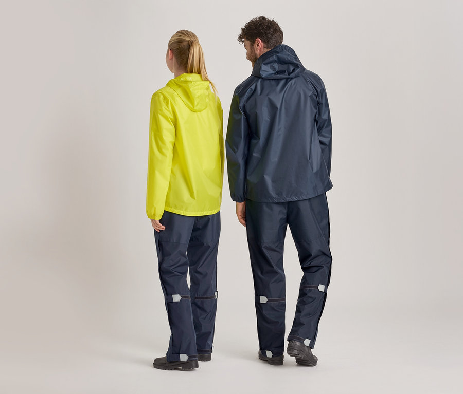 Rückansicht von Frau in gelber Regenjacke und Mann in marineblauer Regenjacke und Regenhose vor hellem Hintergrund.