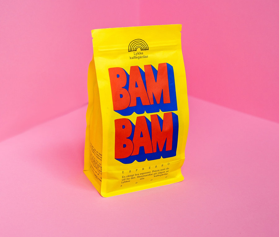 Gelbe Packung Lykke Kaffegårdar Espresso BAM BAM mit roter und blauer Schrift vor rosa Ecke.