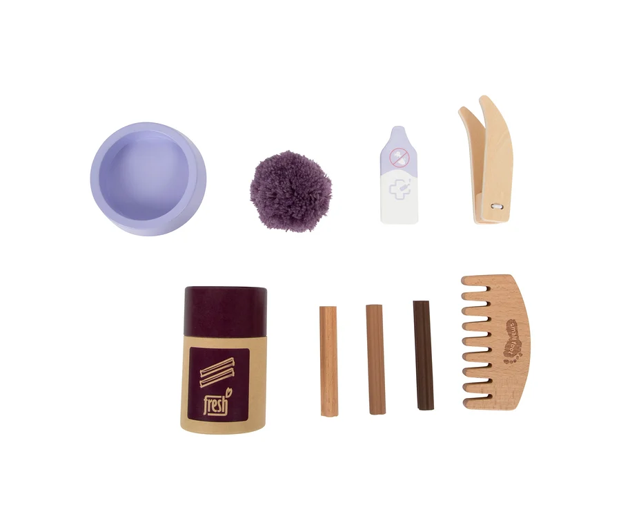 small foot Plüschkatze mit Tasche und Pflege-Set: Ein lila Napf, ein violetter Pompon, ein Spielzeug-Thermometer, eine Holzpinzette, ein Behälter mit der Aufschrift „fresh“, drei Holzstäbchen und ein Holzkamm.