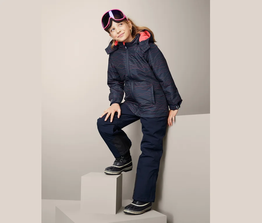 Mädchen posiert in Thermo-Skijacke und Skibrille.