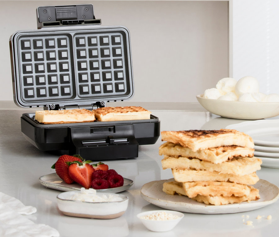 Auf einem Tisch stehen ein schwarzes WILFA Waffeleisen GAUFRES »BW-1000B«, Waffeln, Erdbeeren, Himbeeren, Schlagsahne und Eis.