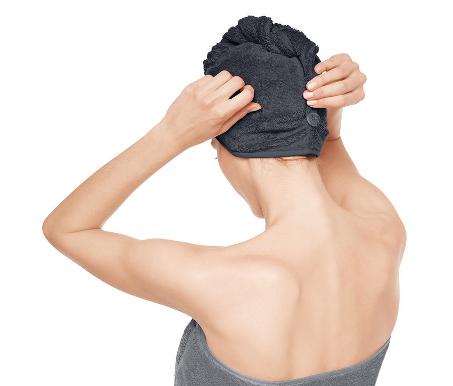 Frau befestigt ein Turban-Handtuch auf ihrem Kopf.