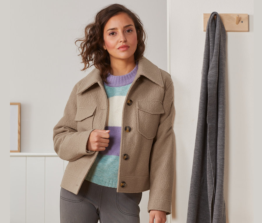 Frau posiert in Teddyjacke und Streifenpullover.