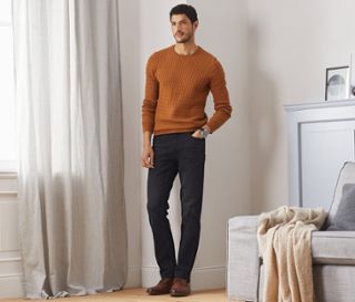 Mann steht im Raum und trägt Jeans.