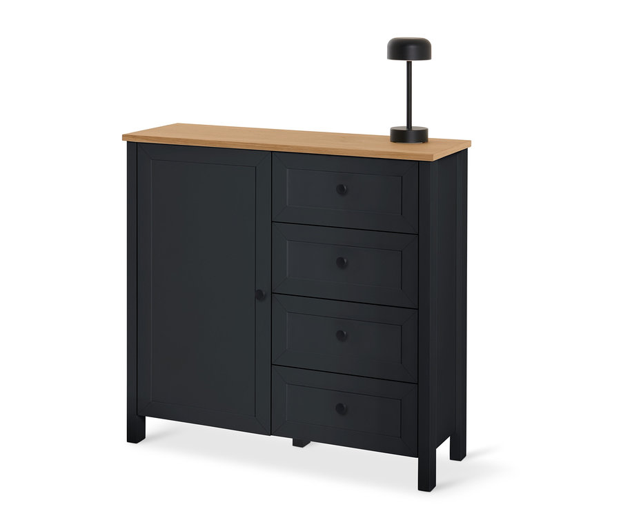 Schwarze Kommode »Clara« mit Schubladen und Tür und einer Holzplatte, auf der eine schwarze Lampe steht.