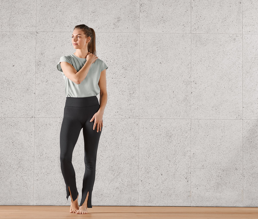 Frau posiert in schwarzer Seamless-Flared-Sporthose mit Schlitz.