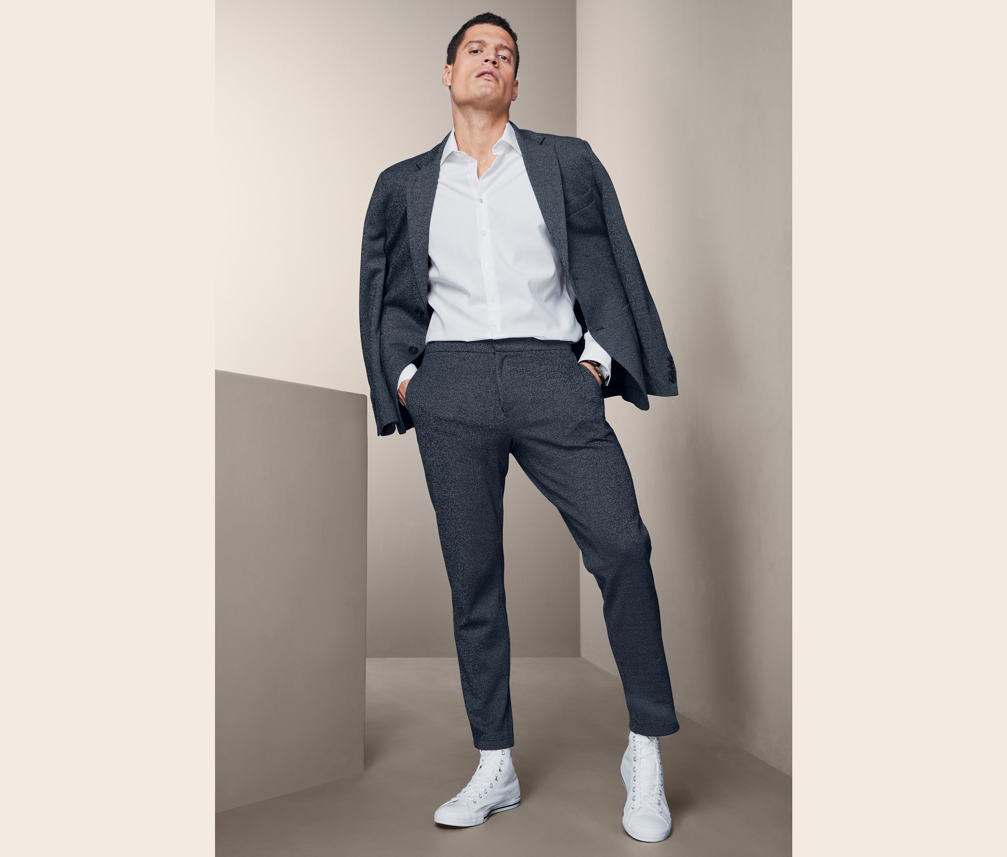 Mann posiert in Sakko, Hemd und Jersey-Hose.