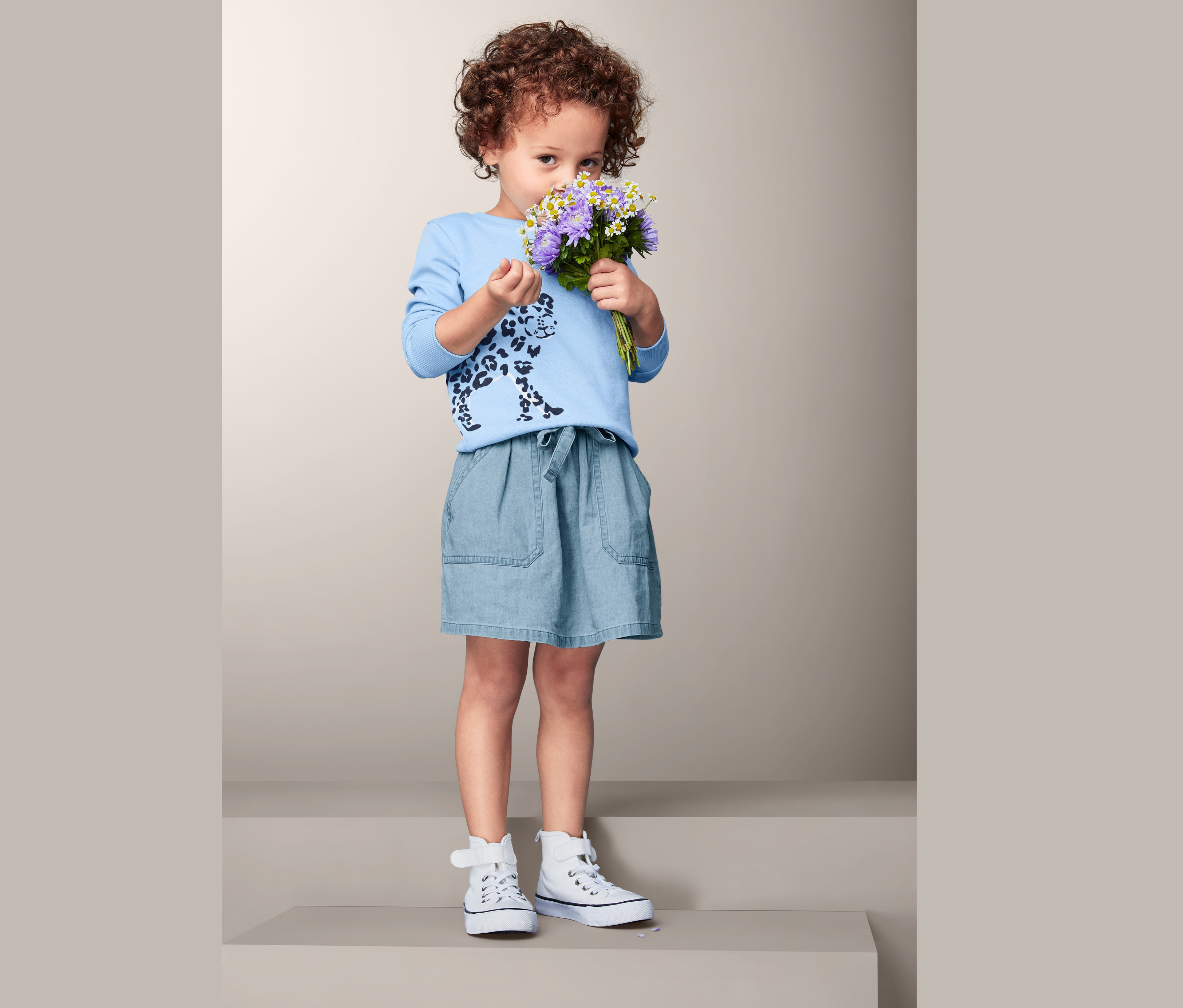 Mädchen hält Blumenstrauß und trägt Baumwoll-Denim-Rock.