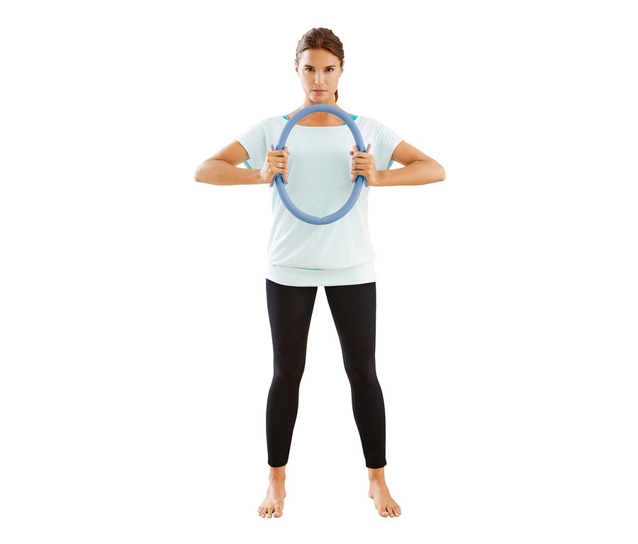 Frau hält einen Pilatesring vor ihrem Gesicht.