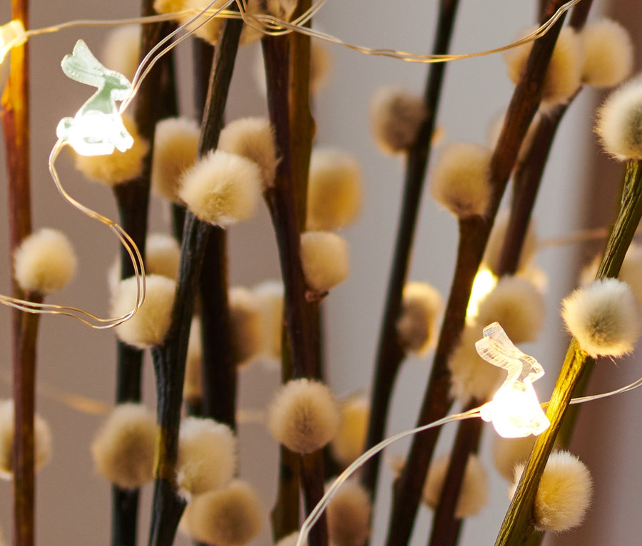 Nahaufnahme von blühenden Zweigen mit LED-Micro-Lichterkette mit Häschen.