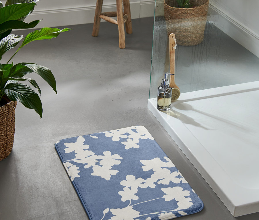 Eine blaue Komfort-Badematte mit Blumenmuster liegt auf dem Boden.
